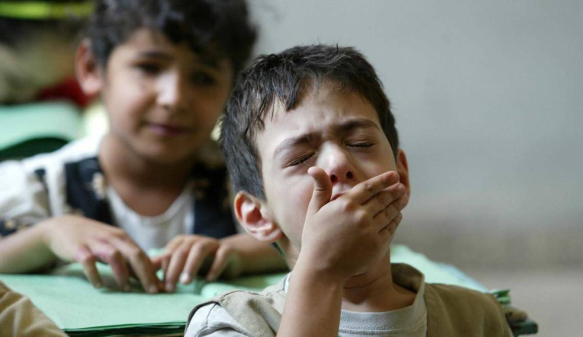A blind Iraqi boy yawns as his classmate